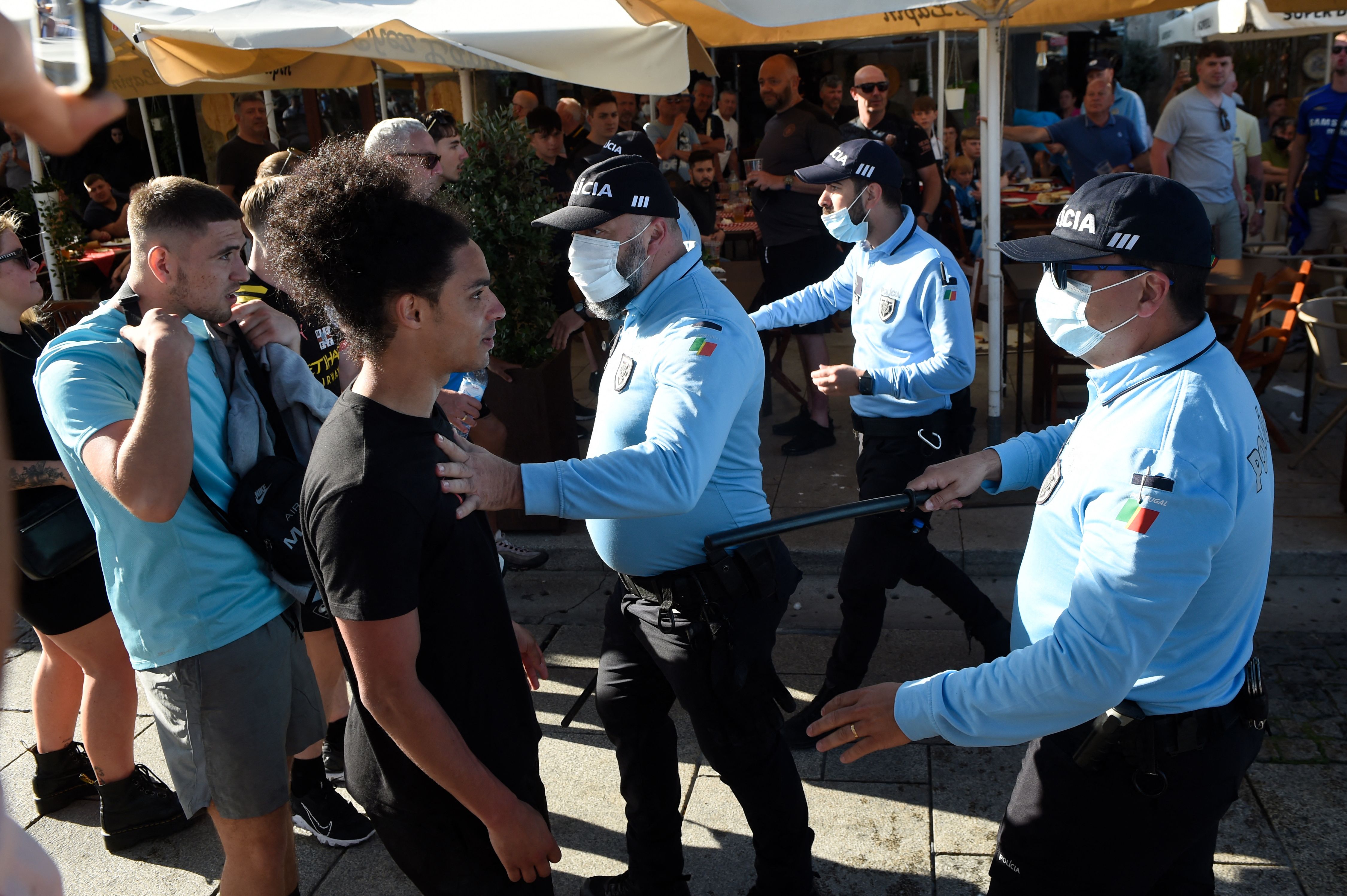 Police with batons try to calm fans outside a bar