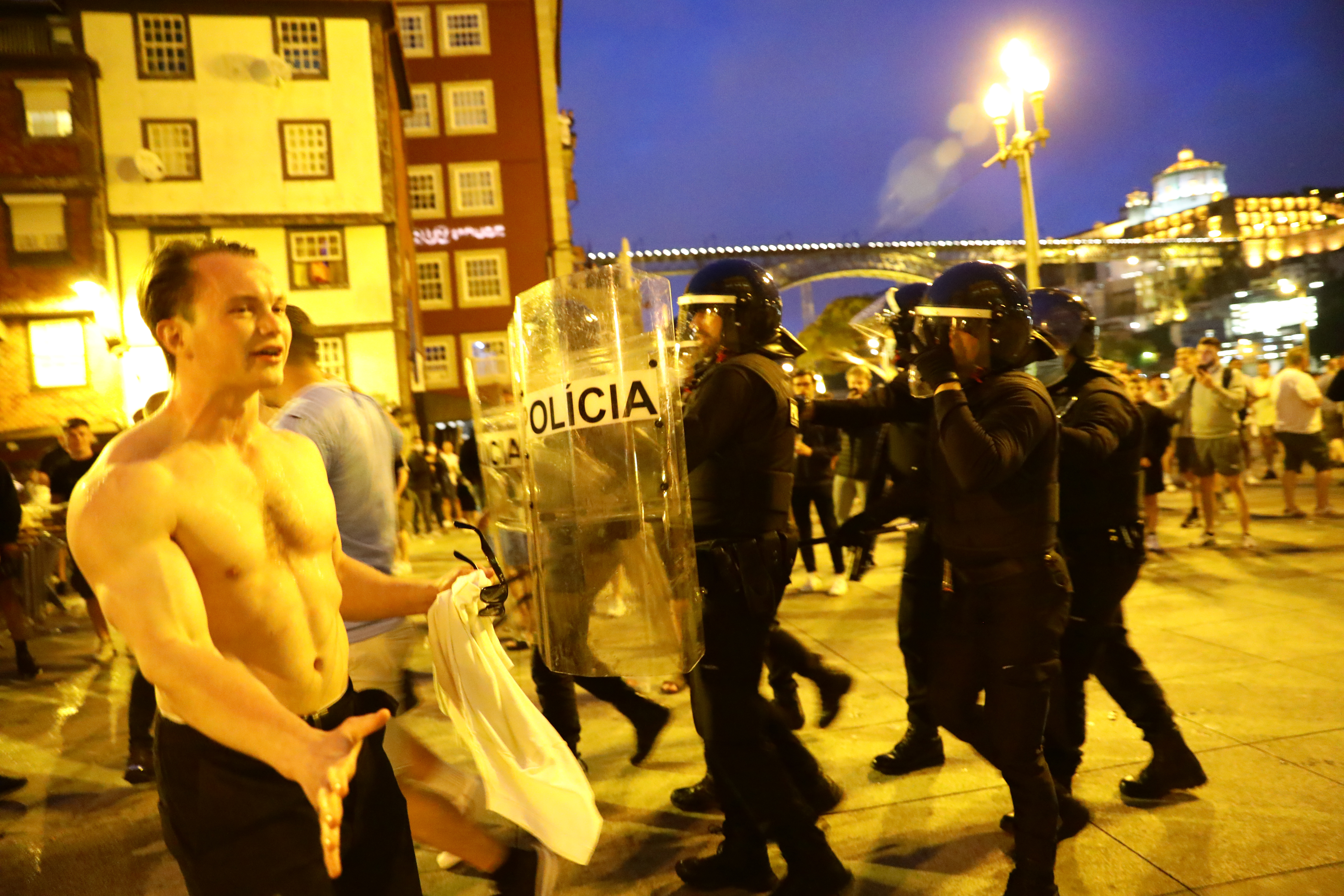 A shirtless man in Porto as riot officers with shields disperse the crowd